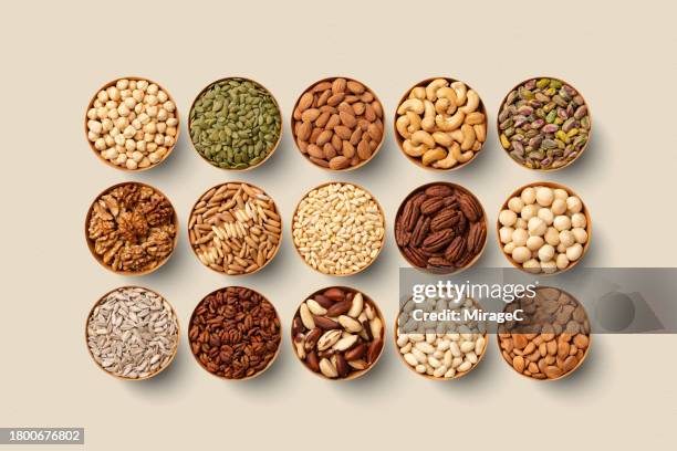 variety of nuts in bowls organized on beige background - sonnenblumenkerne stock-fotos und bilder