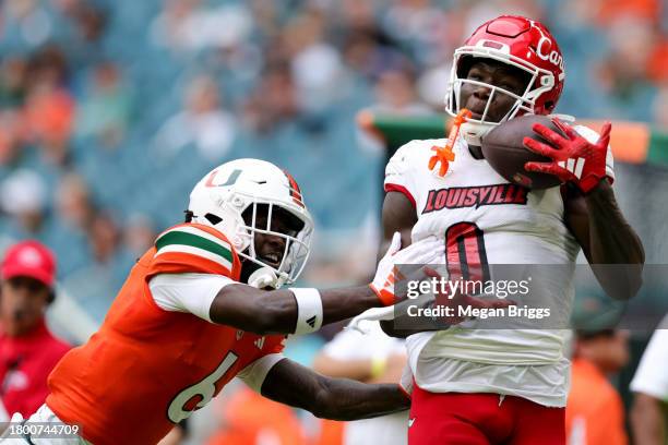 Chris Bell of the Louisville Cardinals catches a pass over Damari Brown of the Miami Hurricanes during the second quarter of the game at Hard Rock...