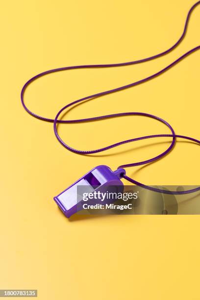 purple whistle with lanyard on yellow background - fluit sportartikelen stockfoto's en -beelden