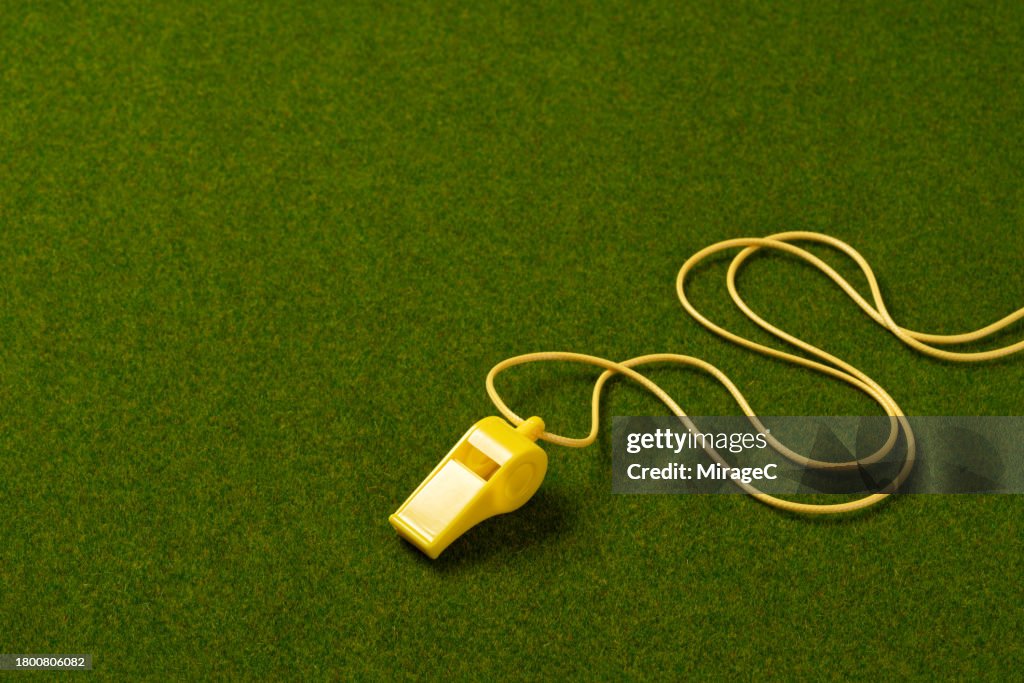 Yellow Whistle With Lanyard on Green Turf Background