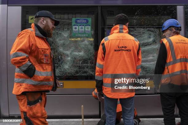 Workers assess the damage to a fire-damaged tram on O'Connell Street, following a night of riots, in Dublin, Ireland, on Friday, Nov. 24, 2023. Irish...