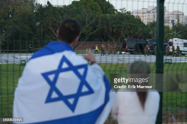 Man wearing an Israeli flag looks toward ambulances outside the Schneider medical centre, where it is believed some of the released hostages may be...