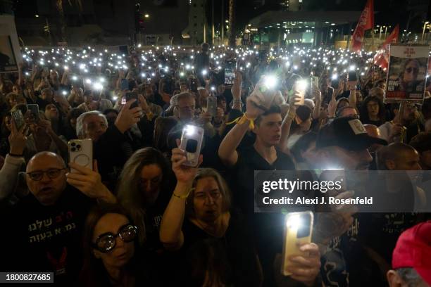 Thousands of people and the families of kidnapped Israelis hold up their mobile phones with the torch light to sing the national anthem during a...