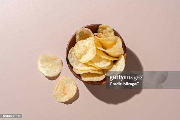 bowl of potato chips on brown background - crisps foto e immagini stock