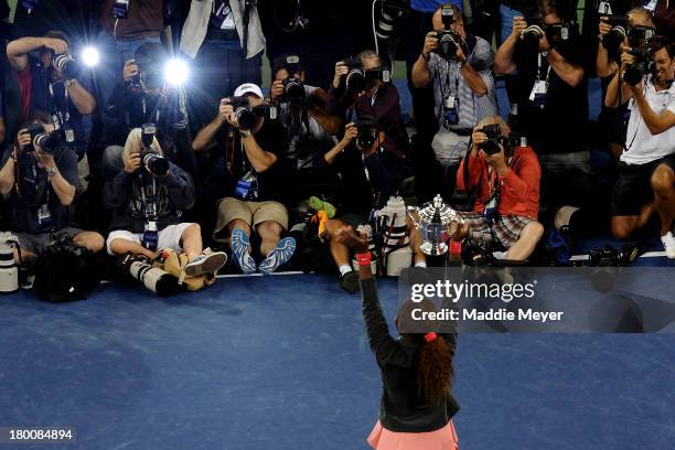 Photographers take pictures of Serena Williams of the United States of America smiles as she poses with the trophy after winning her women's singles...