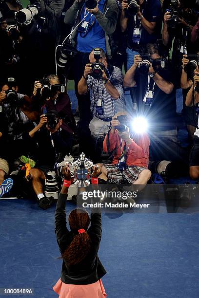 Photographers take pictures of Serena Williams of the United States of America smiles as she poses with the trophy after winning her women's singles...