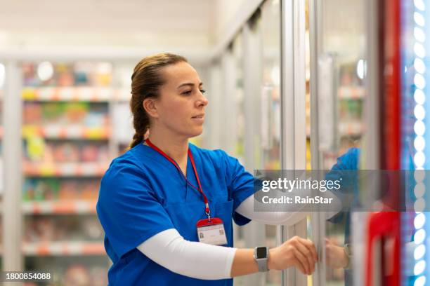 doctora haciendo compras en el supermercado después del trabajo - estantería de productos refrigerados fotografías e imágenes de stock