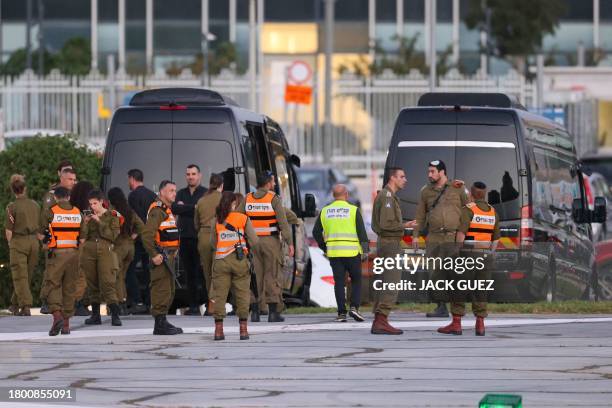 Israeli security forces stand next to buses waiting at the helipad of Tel Aviv's Schneider medical centre on November 24 amid preparations for the...