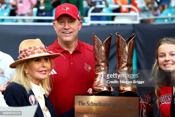 Head coach Jeff Brohm of the Louisville Cardinals receives The Schnellenberger Trophy alongside Beverlee Donnelly after defeating the Miami...