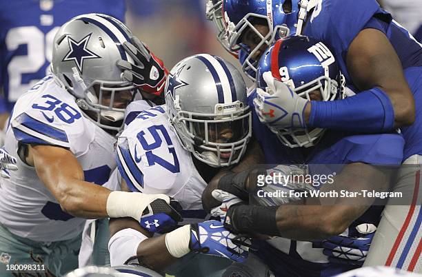 Dallas Cowboys defensive back Jeff Heath and DeVonte Holloman hit New York Giants running back Michael Cox at AT&T Stadium in Arlington, Texas, on...