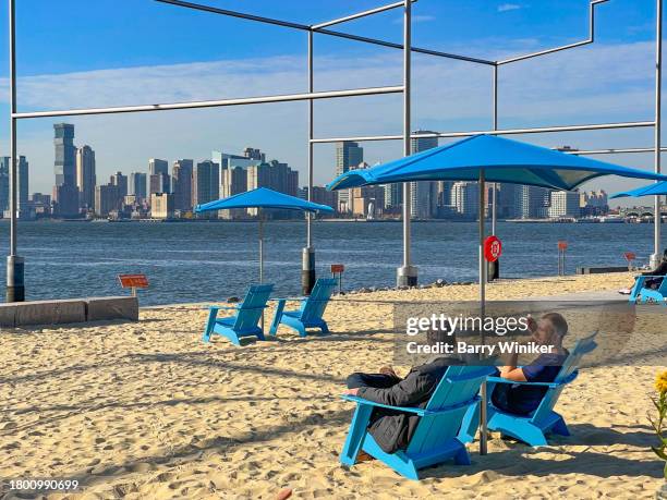 men relaxing at gansevoort peninsula sand bluff, new york - new york basks in sunny indian summer day stock-fotos und bilder