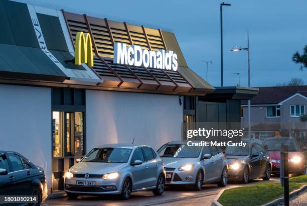 Cars queue to collect their food from the drive thru at the fast food restaurant McDonald's, on November 18, 2023 in Bristol, England. Founded in...