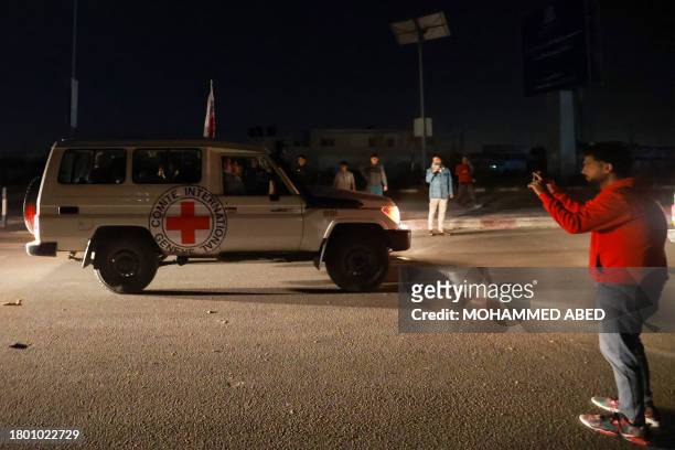 Man takes picture with his mobile of International Red Cross vehicles reportedly carrying hostages released by Hamas as they cross the Rafah border...