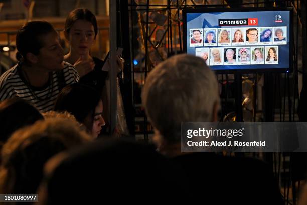 People watch the news broadcasts as hostages are released into Egypt before being brought into Israel by the ICRC, outside the Museum of Tel Aviv on...