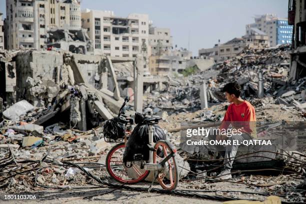 Palestinian youth sits next to his bicycle amid the rubble of destroyed buildings in Gaza City on the northern Gaza strip following weeks of Israeli...