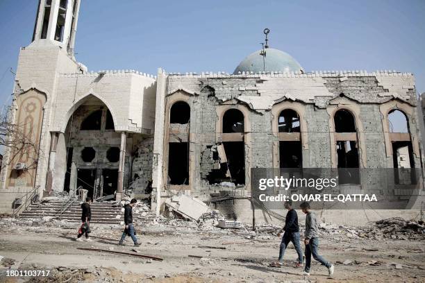 Palestinians holding belongings walk past a destroyed mosque in Gaza City on the northern Gaza strip, following weeks of Israeli bombardment, as a...