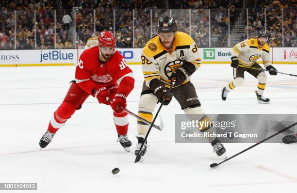 David Pastrnak of the Boston Bruins is checked by Joe Veleno of the Detroit Red Wings during the first period at the TD Garden on November 24, 2023...