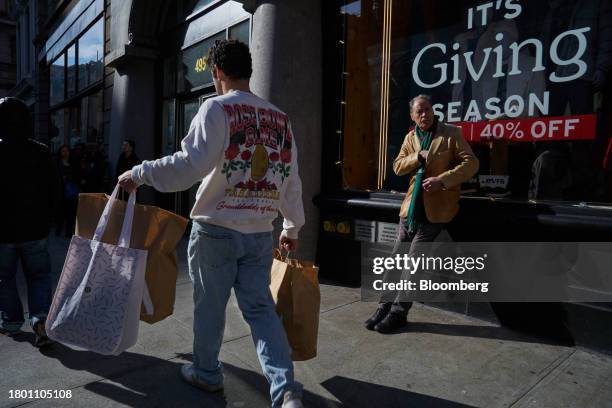 Shopper carries bags on Black Friday in the SoHo neighborhood of New York, US, on Friday, Nov. 24, 2023. An estimated 182 million people are planning...