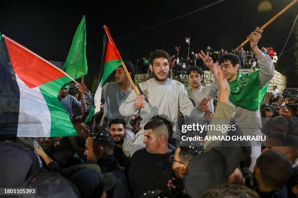 Palestinian prisoners that were released from the Israeli Ofer military facility in exchange for hostages freed by Hamas in Gaza, wave flags and...