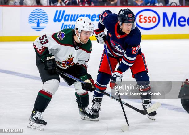 Michael Carcone of the Arizona Coyotes and Nikolaj Ehlers of the Winnipeg Jets prepare for a second period face-off at Canada Life Centre on November...
