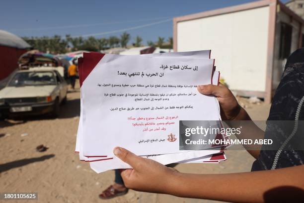 Palestinian boy carries an Israeli flyer, warning citizens of Gaza not to return to the north of the strip, in Khan Yunis in the southern Gaza Strip...