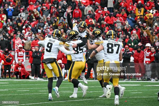 Place kicker Marshall Meeder of the Iowa Hawkeyes is carried by punter Tory Taylor and defensive lineman Logan Lee and tight end Steven Stilianos and...
