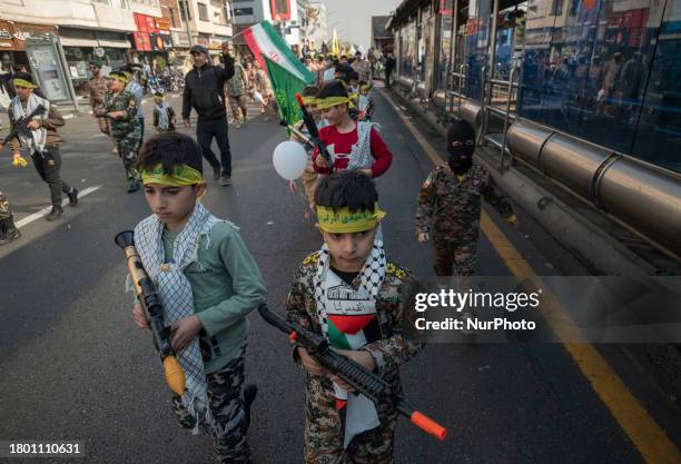 Iranian children are dressed in military uniforms and carrying toy guns as they participate in the Ela Beit Al-Moghaddas military rally in Tehran,...