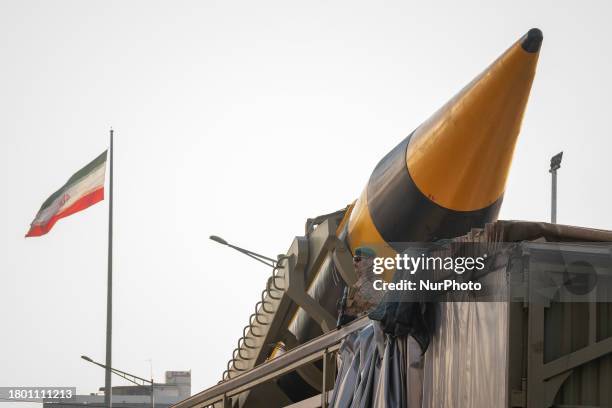 An Islamic Revolutionary Guard Corps armed military personnel is monitoring an area while standing guard next to an Iranian Kheibar...