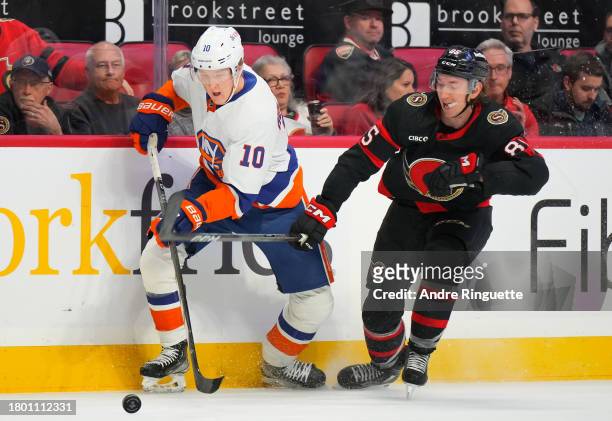 Simon Holmstrom of the New York Islanders battles for puck possession against Jake Sanderson of the Ottawa Senators at Canadian Tire Centre on...