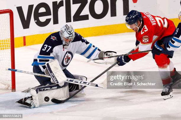 Goaltender Connor Hellebuyck of the Winnipeg Jets defends the net against Carter Verhaeghe of the Florida Panthers at the Amerant Bank Arena on...