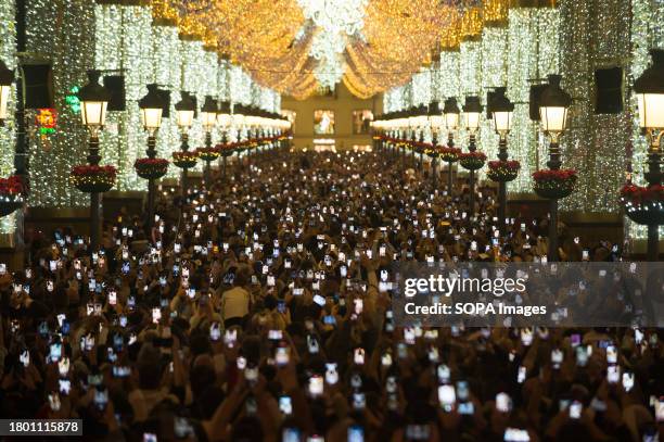 General view of people using their mobile phones while looking at the Christmas lights in Marques de Larios street. Every year, Malaga city turns on...