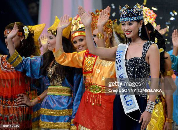 In this photograph taken on September 8 reigning Miss World 2012 Wenxia Yu of China waves with contestants for Miss World 2013 wearing traditional...