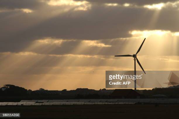 Photo taken on August 9, 2013 shows sun rays over a wind and a solar hybrid parc on the Pellworm island, northern Germany. Home to about 1,000 people...