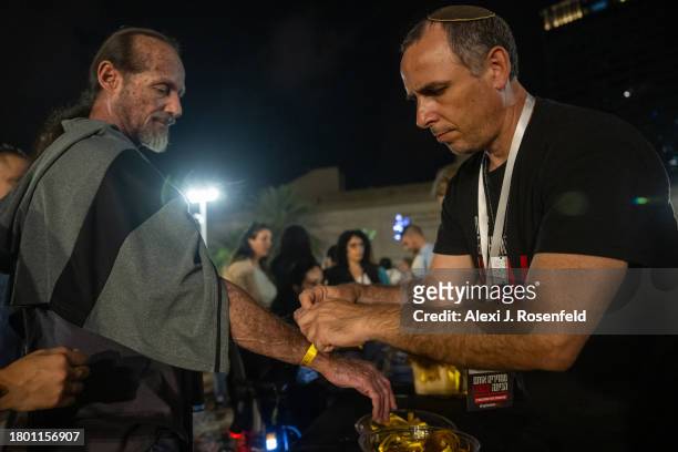 Volunteers tie yellow ribbons on demonstrators that read, "Oct 7. Bring Them Home Now" at a rally to demand that Israeli Prime Minister Benjamin...