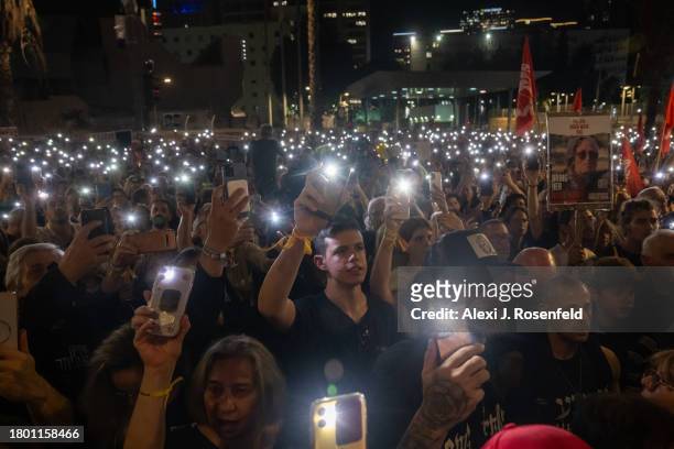 Thousands of people and the families of kidnapped Israelis hold up their mobile phones with the torch light to sing the national anthem during a...