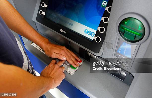 Customer shields their personal identification number as they use an automated teller machine outside a TSB branch, part of the Lloyds Banking Group...