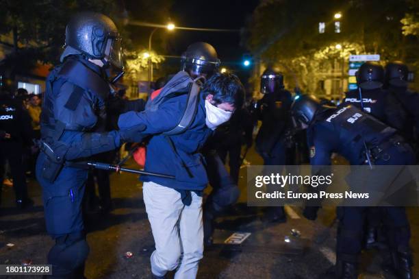 Young man wearing a mask is detained by several police officers during a demonstration against the amnesty in front of the PSOE headquarters in...