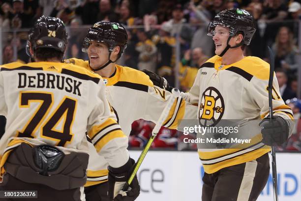 Trent Frederic of the Boston Bruins celebrates with Jake DeBrusk and Hampus Lindholm after scoring a goal against the Montreal Canadiens during the...