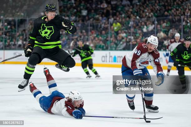 Evgenii Dadonov of the Dallas Stars leaps to avoid Bowen Byram of the Colorado Avalanche as Byram dives for a loose puck with Samuel Girard during...