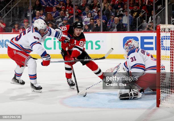 Jack Hughes of the New Jersey Devils heads for the net as Ryan Lindgren and Igor Shesterkin of the New York Rangers defend during the second period...