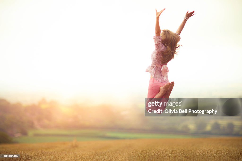 Girl Jumping in Harvested Wheat Field