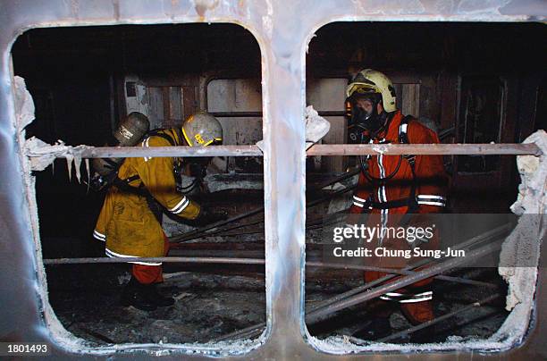 South Korean rescue workers inspect a subway train destroyed by a fire at a subway station February 18, 2003 in Daegu, 200 miles southeast of Seoul,...