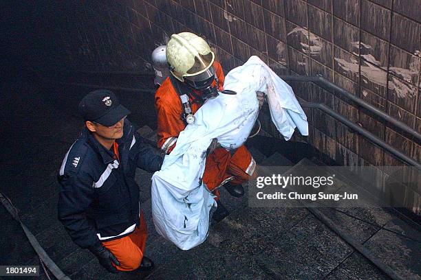 Firefighters carry a victim's body from a subway station February 18, 2003 in Daegu, 200 miles southeast of Seoul, South Korea. About 120 people were...