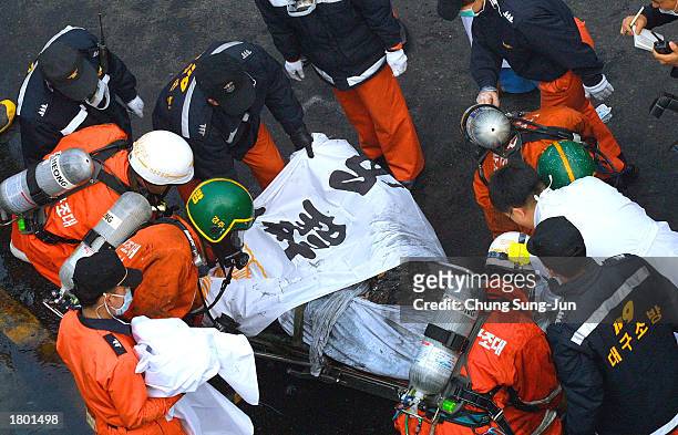 Firefighters cover a burn victim near a subway station February 18, 2003 in Daegu, 200 miles southeast of Seoul, South Korea. About 120 people were...