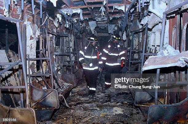 South Korean rescue workers inspect a subway train destroyed by a fire at a subway station February 18, 2003 in Daegu, 200 miles southeast of Seoul,...