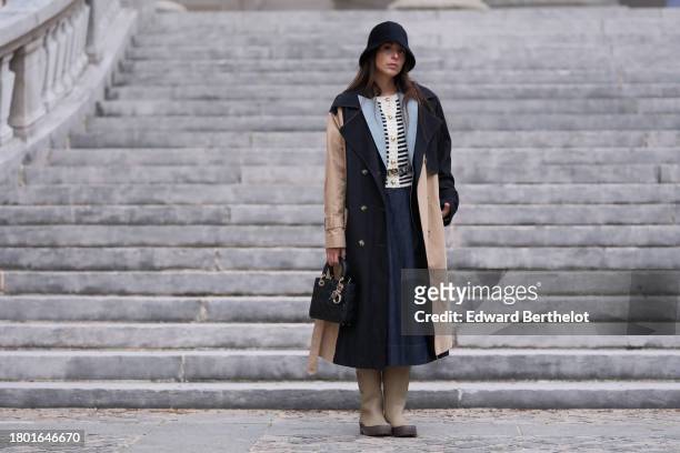 Gabriella Berdugo wears a full Dior look, a black hat, a navy /dark blue blazer jacket with pale / light blue lapels, a black and white striped wool...