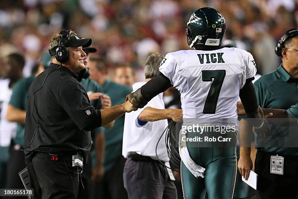 Head coach Chip Kelly of the Philadelphia Eagles smiles as he bumps fists with quarterback Michael Vick in the first half against the Washington...