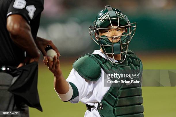 Catcher Kurt Suzuki of the Oakland Athletics gets a fresh ball from the home plate umpire against the Houston Astros in the ninth inning at O.co...