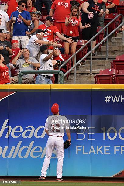 Right fielder Jay Bruce of the Cincinnati Reds watches a home run hit by Ryan Sweeney of the Chicago Cubs in the second inning sail over the wall at...