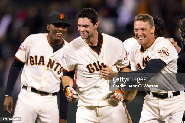 Brandon Belt of the San Francisco Giants is congratulated by Joaquin Arias and Hunter Pence after hitting a walk-off single against the Colorado...
